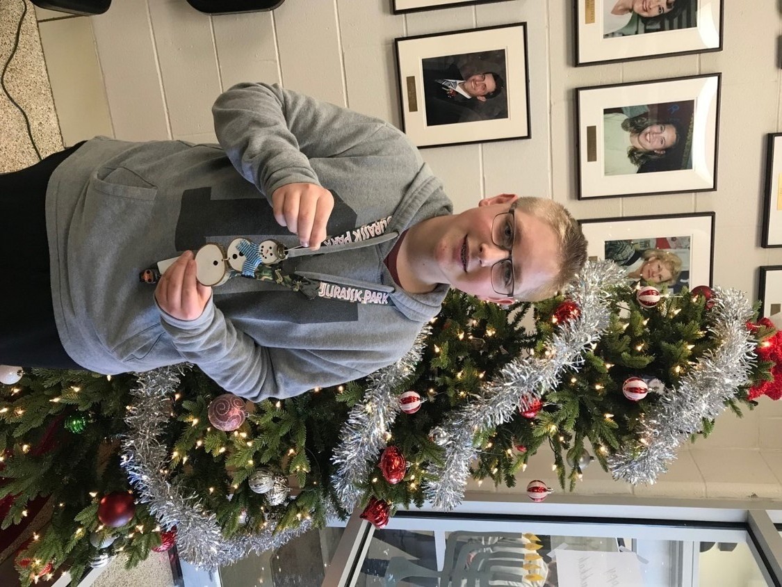 boy holding ornament in front of tree